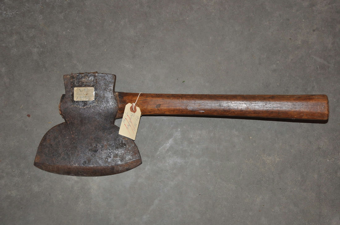 An old hatchet with a worn wooden handle and an evidence tag